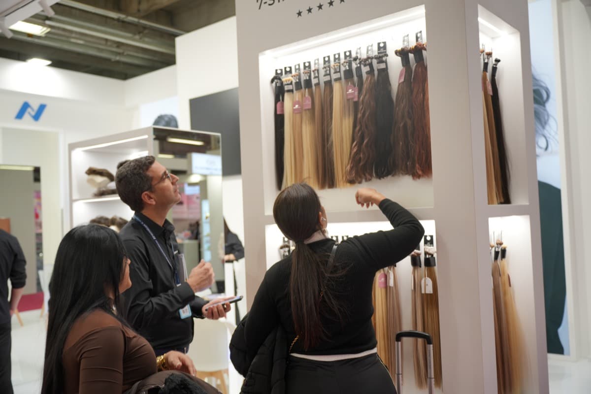 Hair professionals reviewing extension samples on a display wall