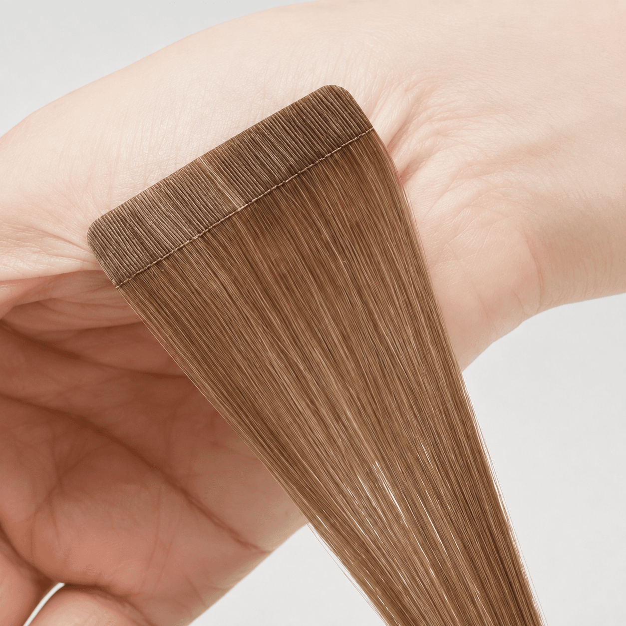 Brown tape-in hair extension held for construction inspection