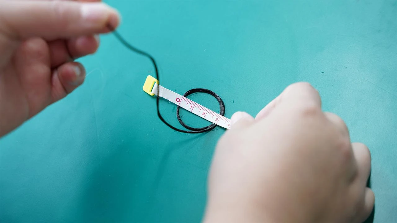 Measuring a dark brown hair extension sample with a tape measure to check hair fullness ratio and end density for salon bulk order quality control.