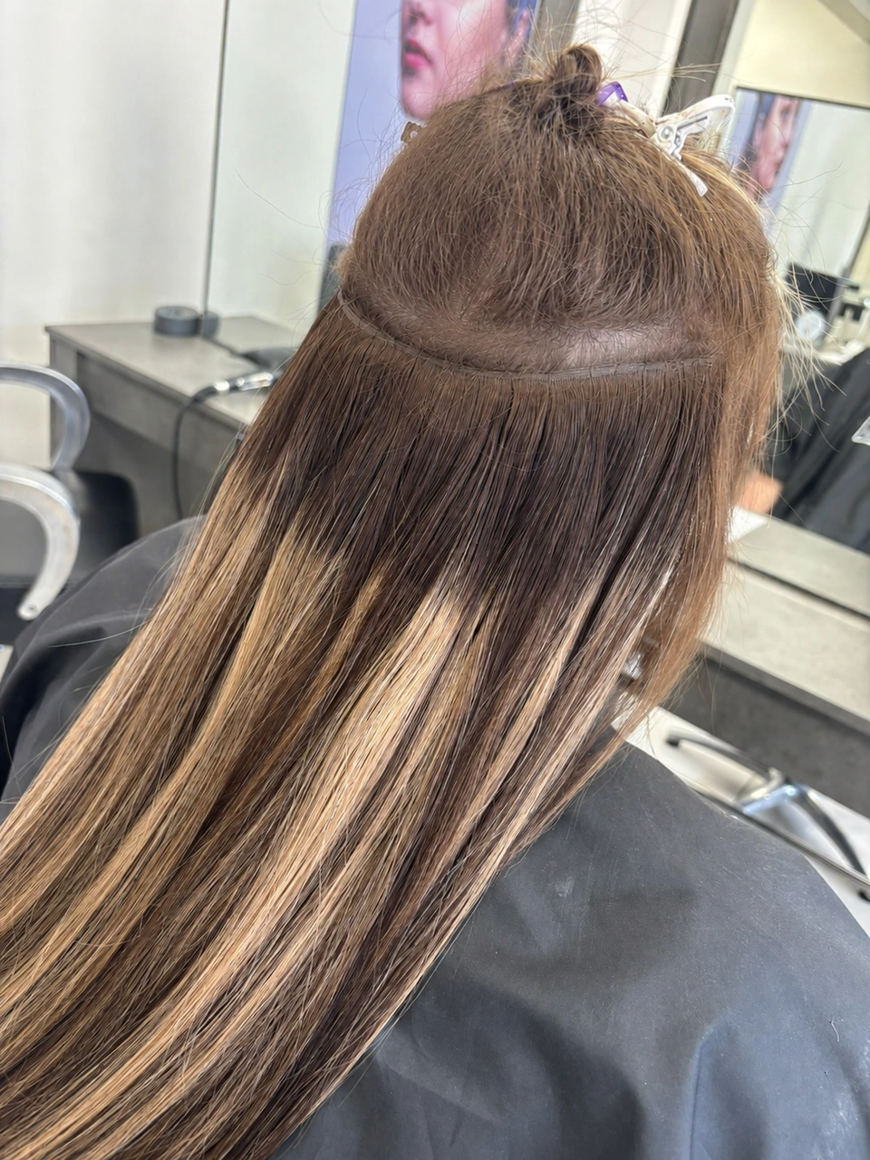 Salon weft hair extension installation showing row placement and weight distribution on a client with fine hair.