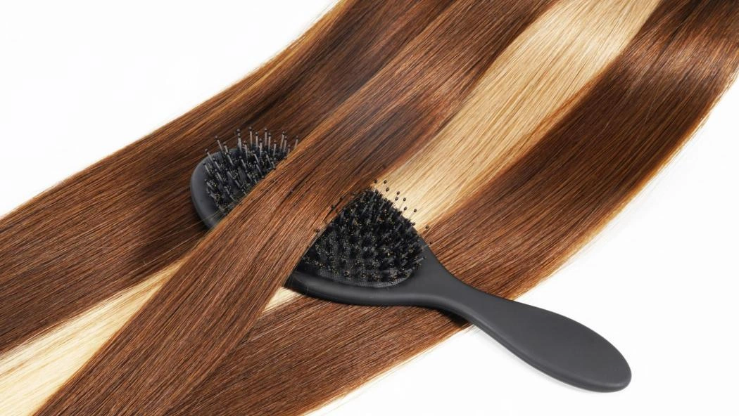 Smooth Remy human hair extensions being brushed to show quality, shine, and manageability for salon services.