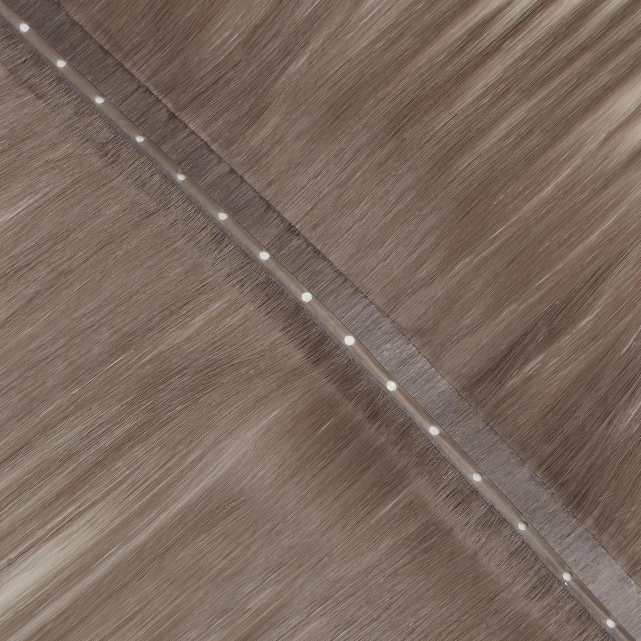 Close-up of a Invisi Flip Weft with center-positioned bead holes and a flat PU attachment area for discreet root placement.